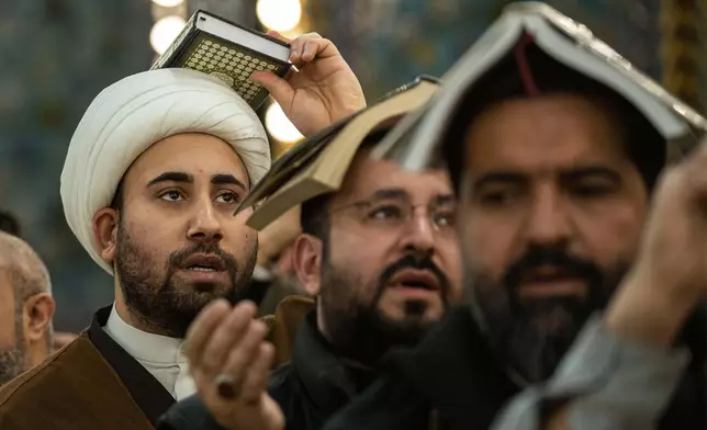 Shiite worshippers place copies of the Quran on their heads during Laylat al-Qadr, or the Night of Destiny, in the holy fasting month of Ramadan at the shrine of Imam Abbas in Karbala, Iraq, Sunday, March 23, 2025. (AP Photo/Hadi Mizban)