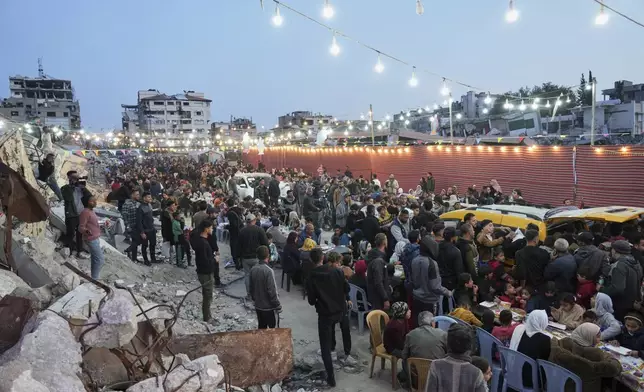 Palestinians sit at a large table surrounded by the rubble of destroyed homes and buildings as they gather for iftar, the fast-breaking meal, during Ramadan in Gaza City, Thursday March 6, 2025 (AP Photo/Abdel Kareem Hana)