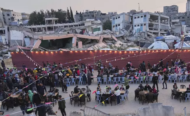 Palestinians sit at a large table surrounded by the rubble of destroyed homes and buildings as they gather for Iftar, the fast-breaking meal, during Ramadan in Gaza City, Thursday March 6, 2025 (AP Photo/Abdel Kareem Hana)