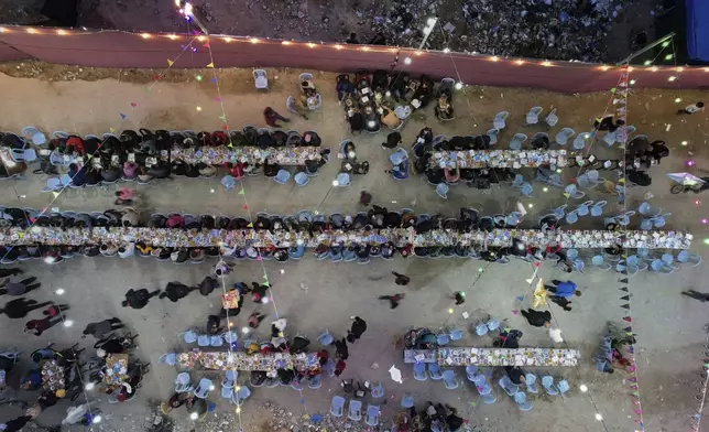 Palestinians sit at a large table as they gather for Iftar, the fast-breaking meal, during Ramadan in Gaza City, Thursday March 6, 2025. (AP Photo/Mohammad Abu Samra)