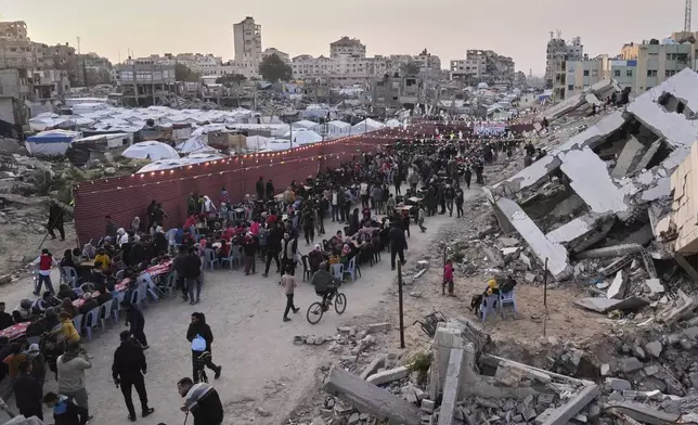 Palestinians sit at a large table surrounded by the rubble of destroyed homes and buildings as they gather for iftar, the fast-breaking meal, during Ramadan in Gaza City, Thursday March 6, 2025 (AP Photo/Abdel Kareem Hana)