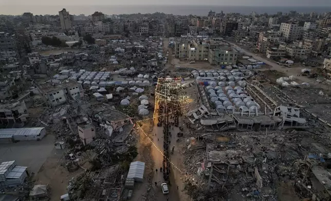 Palestinians sit at a large table surrounded by tents and the rubble of destroyed homes and buildings as they gather for Iftar, the fast-breaking meal, during Ramadan in Gaza City, Thursday March 6, 2025.(AP Photo/Mohammad Abu Samra)