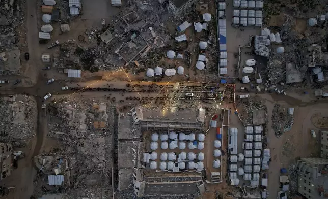 Palestinians sit at a large table surrounded by tents and the rubble of destroyed homes and buildings as they gather for Iftar, the fast-breaking meal, during Ramadan in Gaza City, Thursday March 6, 2025.(AP Photo/Mohammad Abu Samra)