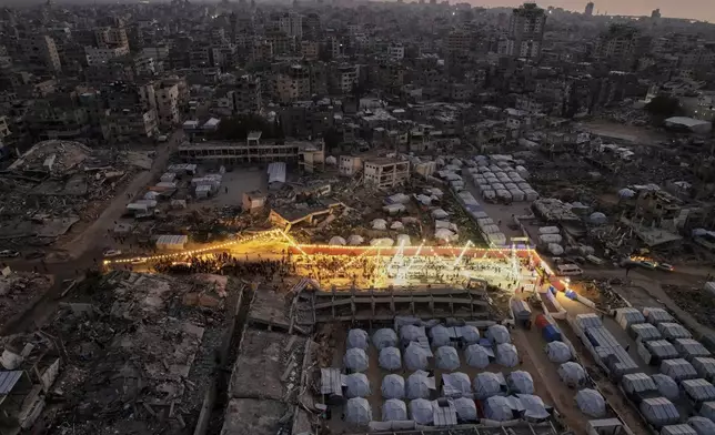 Palestinians sit at a large table surrounded by tents and the rubble of destroyed homes and buildings as they gather for Iftar, the fast-breaking meal, during Ramadan in Gaza City, Thursday March 6, 2025.(AP Photo/Mohammad Abu Samra)