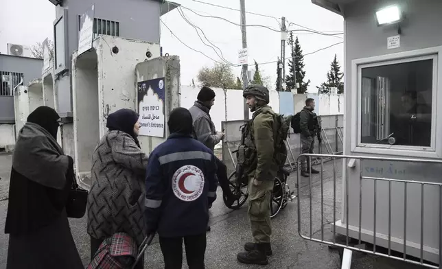 An Israeli soldier speaks to a Palestinian woman at a checkpoint in the West Bank city of Bethlehem, on her way to the Al-Aqsa Mosque compound in Jerusalem for the first Friday Prayers of the Muslim holy month of Ramadan, Friday, March 7, 2025. (AP Photo/Mahmoud Illean)