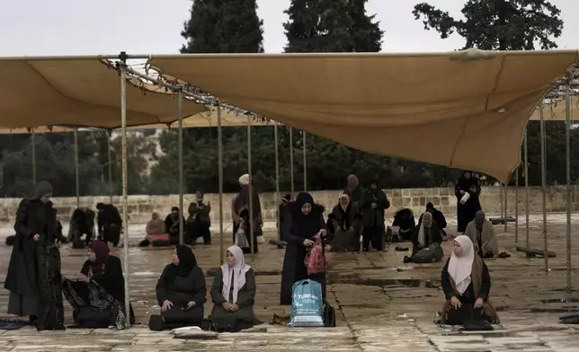 Women take cover from the rain near the Dome of the Rock Mosque at the Al-Aqsa Mosque compound for the first Friday Prayers of the Muslim holy month of Ramadan in the Old City of Jerusalem, Friday, March 7, 2025. (AP Photo/Mahmoud Illean)