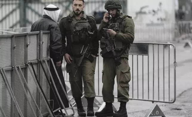 Israeli soldiers check a Palestinian man's ID at a checkpoint in the West Bank city of Bethlehem, on his way to the Al-Aqsa Mosque compound in Jerusalem for the first Friday Prayers of the Muslim holy month of Ramadan, Friday, March 7, 2025. (AP Photo/Mahmoud Illean)