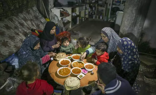 Fatima Al-Absi, left, shares Iftar, the fast-breaking meal, with her daughter and grandchildren on the first day of Ramadan in their damaged apartment in Jabaliya, northern Gaza Strip, on Saturday, March 1, 2025. (AP Photo/Jehad Alshrafi)