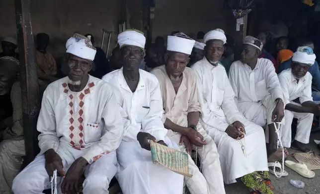Less privileged men raise waits to collect ramadan cook jollof rice and Chicken in Lagos, Nigeria, Tuesday, March 11, 2025. (AP Photo/Sunday Alamba)