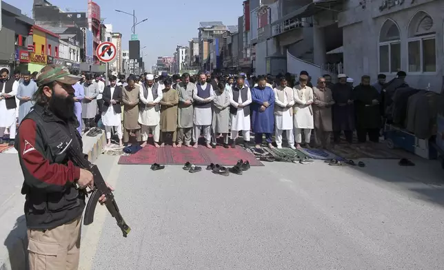 A police officer stands guard as Muslims attend first Friday prayers during the Muslim holy fasting month of Ramadan, at the outer area of a mosque, in Peshawar, Pakistan, Friday, March 7, 2025. (AP Photo/Muhammad Sajjad)