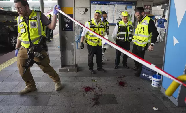 Members of ZAKA rescue services clean blood stains at the scene of a stabbing attack in Haifa, Israel, on Monday, March 30, 2025, where a 70-year-old man was killed and four others were injured. (AP Photo/Ariel Schalit)