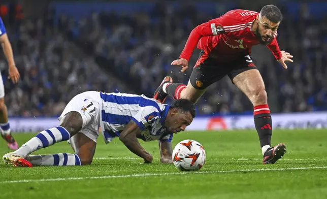 Real Sociedad's Sheraldo Becker, left, challenges for the ball with Manchester United's Noussair Mazraoui during the Europa League round of 16 first leg soccer match between Real Sociedad and Manchester United at the Reale Arena in San Sebastian, Spain, Thursday, March 6, 2025. (AP Photo/Miguel Oses)