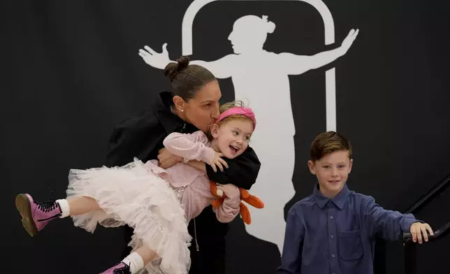 Former Phoenix Mercury player Diana Taurasi kisses daughter Isla, as son Leo Michael looks on after her retirement news conference, Thursday, March 13, 2025, in Phoenix. (AP Photo/Matt York)