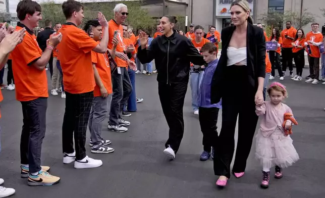 Former Phoenix Mercury player Diana Taurasi, left, greets Mercury employees as she arrives for her retirement news conference with wife, Penny Taylor, and their children Leo Michael, and Isla, right, Thursday, March 13, 2025, in Phoenix. (AP Photo/Matt York)