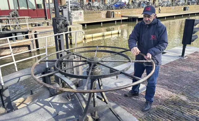 Rashid Ouchene opens the lock in Utrecht, Netherlands, Tuesday, March 11, 2025, where a "fish doorbell" was installed that lets viewers of an online livestream alert authorities to fish being held up as they make their springtime migration to shallow spawning grounds. (AP Photo/Aleksandar Furtula)