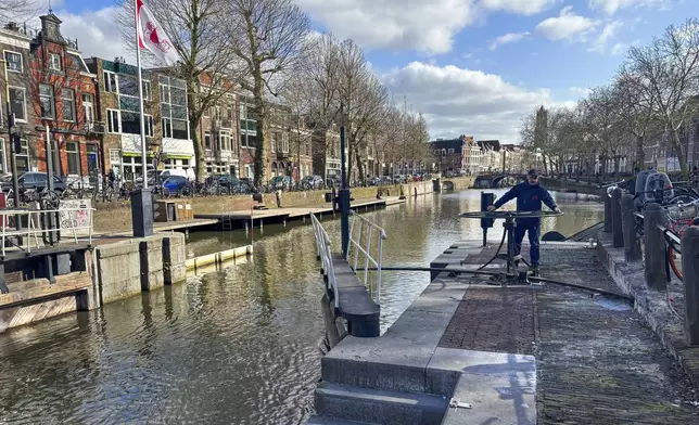 Rashid Ouchene opens the lock in Utrecht, Netherlands, Tuesday, March 11, 2025, where a "fish doorbell" was installed that lets viewers of an online livestream alert authorities to fish being held up as they make their springtime migration to shallow spawning grounds. (AP Photo/Aleksandar Furtula)