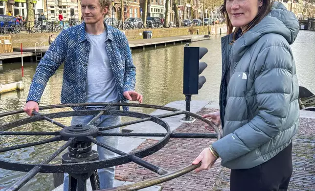 Anna Nijs, ecologist with the Utrecht municipality, right, and Mark van Heukelum, ecologist and concept developer, pose at the the lock in the city of Utrecht, Netherlands, Tuesday, March 11, 2025, where a "fish doorbell" was installed that lets viewers of an online livestream alert authorities to fish being held up as they make their springtime migration to shallow spawning grounds. (AP Photo/Aleksandar Furtula)