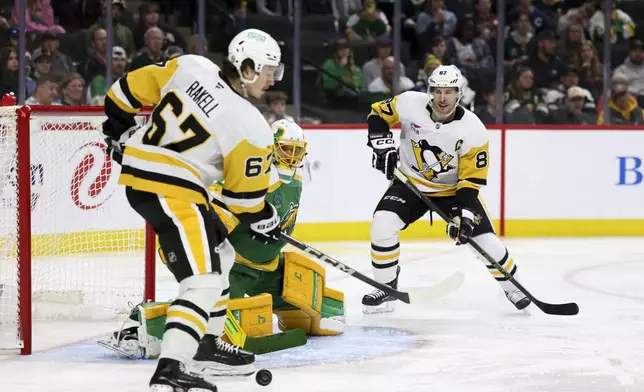 Pittsburgh Penguins right wing Rickard Rakell (67) and center Sidney Crosby (87) attempt to score while Minnesota Wild goaltender Marc-Andre Fleury (29) guards the net during the second period of an NHL hockey game, Sunday, March 9, 2025, in St. Paul, Minn. (AP Photo/Ellen Schmidt)
