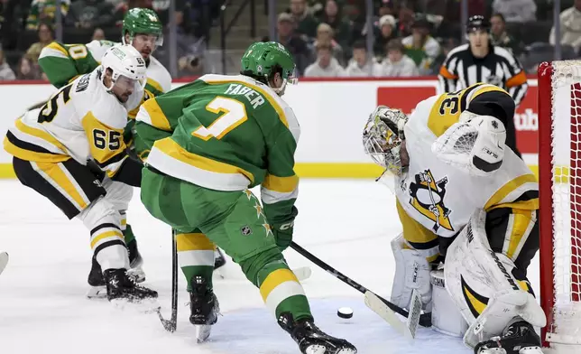 Minnesota Wild defenseman Brock Faber (7) attempts a goal against Pittsburgh Penguins goaltender Tristan Jarry, front right, during the first period of an NHL hockey game, Sunday, March 9, 2025, in St. Paul, Minn. (AP Photo/Ellen Schmidt)