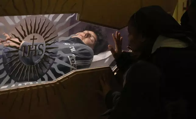The body of Carlo Acutis, an Italian boy who died in 2006 of leukemia, lies in his tomb in Assisi, Italy, on Saturday, March 1, 2025. (AP Photo/Gregorio Borgia)