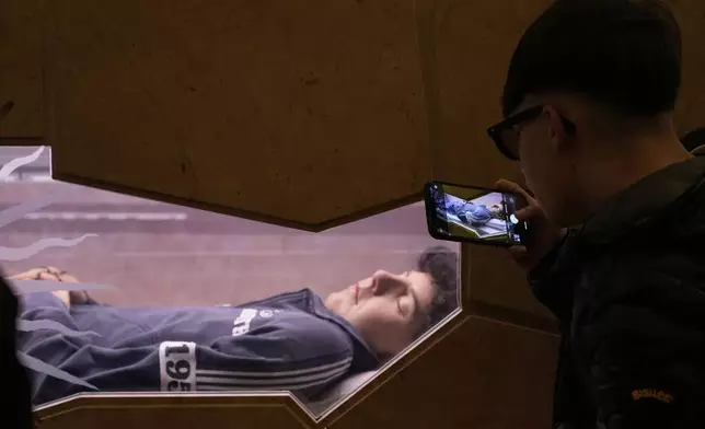 A teenager uses a smartphone to take a picture at the tomb of 15-year-old Carlo Acutis, an Italian boy who died in 2006 of leukemia, in Assisi, Italy, on Saturday, March 1, 2025. (AP Photo/Gregorio Borgia)