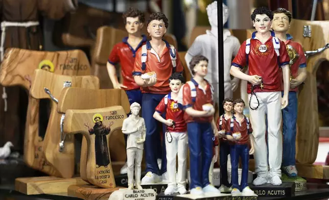 Statuettes of Carlo Acutis, an Italian boy who died in 2006 of leukemia, are displayed for sale in a shop in Assisi, Italy, on Saturday, March 1, 2025. (AP Photo/Gregorio Borgia)