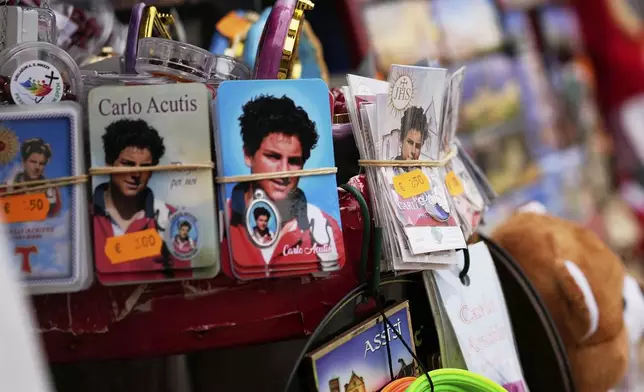 Pictures of 15-year-old Carlo Acutis, an Italian boy who died in 2006 of leukemia, are displayed for sale at a kiosk in Assisi, Italy, on Saturday, March 1, 2025. (AP Photo/Gregorio Borgia)