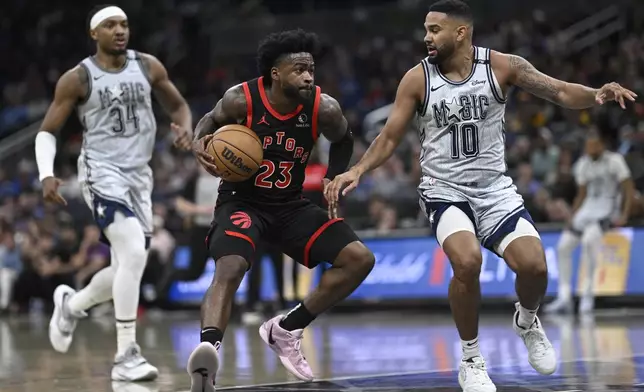 Toronto Raptors guard Jamal Shead (23) drives to the basket as Orlando Magic center Wendell Carter Jr. (34) and guard Cory Joseph (10) defend during the first half of an NBA basketball game, Tuesday, March 4, 2025, in Orlando, Fla. (AP Photo/Phelan M. Ebenhack)