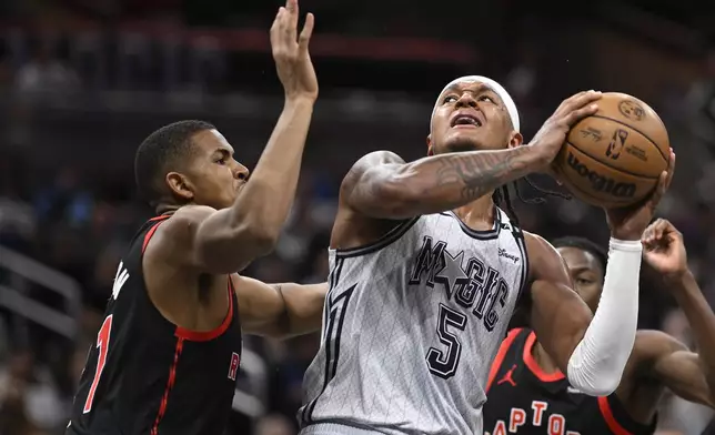 Orlando Magic forward Paolo Banchero (5) tries to shoot as Toronto Raptors center Orlando Robinson, left, defends during the first half of an NBA basketball game, Tuesday, March 4, 2025, in Orlando, Fla. (AP Photo/Phelan M. Ebenhack)