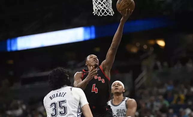 Toronto Raptors forward Scottie Barnes (4) goes up to shoot between Orlando Magic center Goga Bitadze (35) and forward Paolo Banchero, right, during the first half of an NBA basketball game, Tuesday, March 4, 2025, in Orlando, Fla. (AP Photo/Phelan M. Ebenhack)