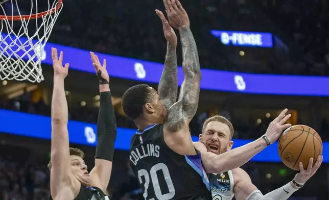 Minnesota Timberwolves guard Donte DiVincenzo, right, attempts a shot in the final seconds an NBA basketball game as Utah Jazz center Walker Kessler, left, and forward John Collins (20) defend during the second half Friday, Feb. 28, 2025, in Salt Lake City. (AP Photo/Rick Egan)