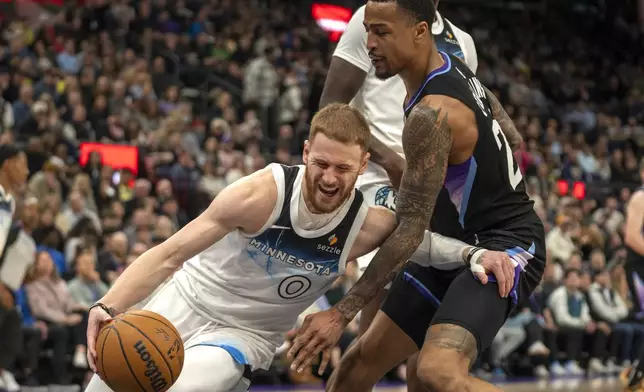 Minnesota Timberwolves guard Donte DiVincenzo (0) dribbles under the hoop, as Utah Jazz forward John Collins, right, defends during the first half of an NBA basketball game Friday, Feb. 28, 2025, in Salt Lake City. (AP Photo/Rick Egan)