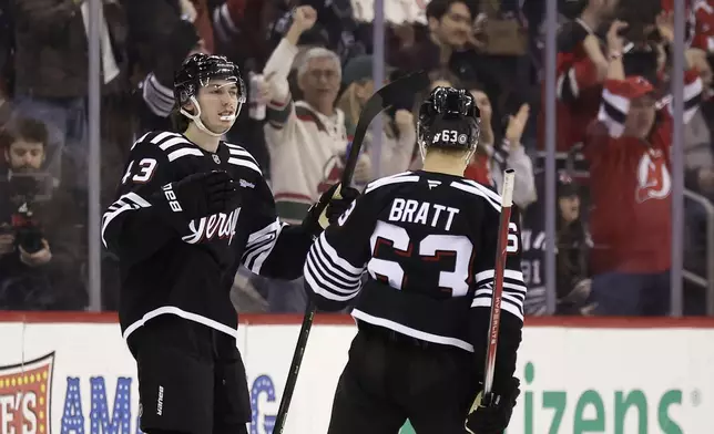 New Jersey Devils defenseman Luke Hughes (43) is congratulated after scoring a goal by Jesper Bratt (63) during the third period of an NHL hockey game against the Columbus Blue Jackets, Tuesday, March 11, 2025, in Newark, N.J. (AP Photo/Adam Hunger)