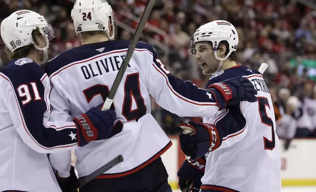 Columbus Blue Jackets right wing Mathieu Olivier (24) is congratulated by Denton Mateychuk (5) and Kent Johnson (91) after scoring a goal in the third period of an NHL hockey game Tuesday, March 11, 2025, in Newark, N.J. (AP Photo/Adam Hunger)
