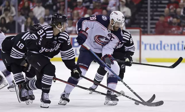 Columbus Blue Jackets center Boone Jenner (38) battles for the puck with New Jersey Devils center Dawson Mercer (91) during the first period of an NHL hockey game Tuesday, March 11, 2025, in Newark, N.J. (AP Photo/Adam Hunger)