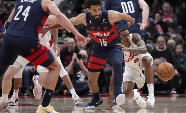 Washington Wizards forward Anthony Gill (16) and Toronto Raptors guard Jared Rhoden (8) vie for the ball during first-half NBA basketball game action in Toronto, Monday, March 10, 2025. (Nathan Denette/The Canadian Press via AP)