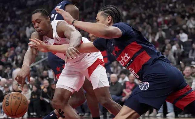 Toronto Raptors forward Scottie Barnes, left, vies for control of the ball with Washington Wizards forward Kyshawn George, right, during first-half NBA basketball game action in Toronto, Monday, March 10, 2025. (Nathan Denette/The Canadian Press via AP)