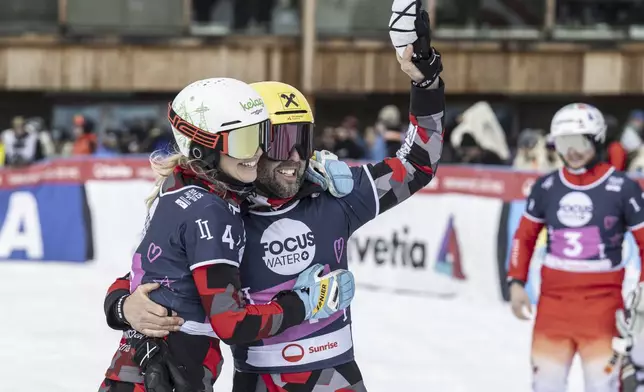 Bronze medalist Sabine Payer of Austria and Andreas Prommegger of Austria celebrate in the finish area at the Snowboard Alpine Parallel-Slalom competition at the FIS Snowboard, Freestyle and Freeski World Championships, Sunday, March 23, 2025, in St. Moritz, Switzerland. (Gian Ehrenzeller/Keystone via AP)