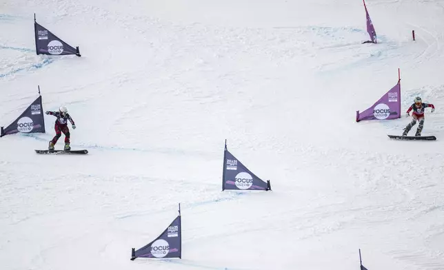 Julie Zogg of Switzerland, right, and Sabine Peyer of Austria, in action during the small final at the Snowboard Alpine Parallel-Slalom competition at the FIS Snowboard, Freestyle and Freeski World Championships, Sunday, March 23, 2025, in St. Moritz, Switzerland. (Gian Ehrenzeller/Keystone via AP)