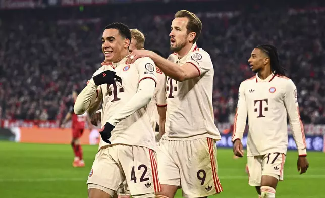 Munich's Jamal Musiala, left, celebrates with his teammate Harry Kane, center, after scoring his side's second goal during the Champions League round of 16 first leg soccer match between FC Bayern Munich and Bayer 04 Leverkusen in Munich, Germany, Wednesday, March 5, 2025. (Tom Weller/dpa via AP)