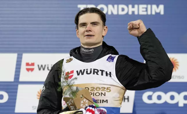 Marius Lindvik, of Norway, celebrates on the podium after winning the gold medal in the ski jumping men's normal hill HS102 event at the Nordic World Ski Championships in Trondheim, Norway, Sunday, March 2, 2025. (AP Photo/Matthias Schrader)