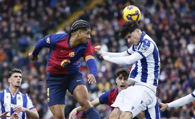 Barcelona's Ronald Araujo, left, and Real Sociedad's Jon Martin jump for the ball during the Spanish La Liga soccer match between Barcelona and Real Sociedad at the Lluis Companys Olympic Stadium in Barcelona, Spain, Sunday, March 2, 2025. (AP Photo/Joan Monfort)