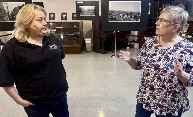 Jackson County Historical Society President Laura Cates Duncan, right, and Mary Riseling, a society board member and coordinator of the 100th anniversary commemoration of the Tri-State Tornado, discuss the March 18, 1925 cataclysm while standing among a gallery of photos on display at the society's office on March 11, 2025 in Murphysboro, Ill. (AP Photo/John O'Connor)