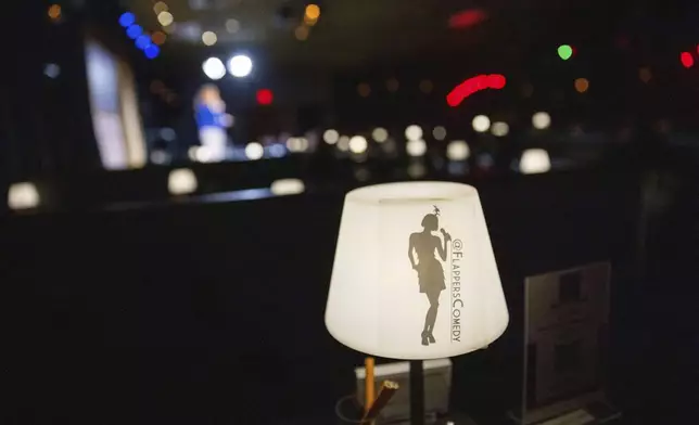 A light with the name Flappers Comedy is visible as Ashley Brooke Roberts performs during Stand Up For Climate on Thursday, March 20, 2025, in Burbank, Calif. (AP Photo/Ethan Swope)