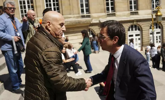 Yunice Abbas, left, one of the men accused in the 2016 armed robbery of Kim Kardashian, shakes hands with his lawyer Gabriel Dumenil outside the palace of justice Monday, April 28, 2025 in Paris. (AP Photo/Aurelien Morissard)