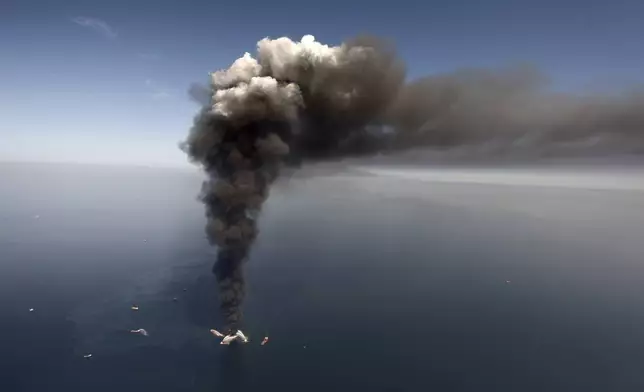FILE - Oil leaks in the Gulf of Mexico southeast of Venice on Louisiana's tip, as the Deepwater Horizon oil rig burns on April 21, 2010. (AP Photo/Gerald Herbert, File)