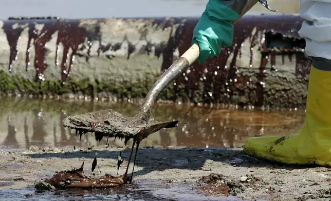 FILE - A worker shovels oil from the Deepwater Horizon oil spill off Fourchon Beach in Port Fourchon, La., May 24, 2010. (AP Photo/Patrick Semansky, File)