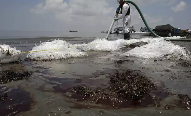 FILE - A worker uses a suction hose to remove oil washed ashore from the Deepwater Horizon spill, in Belle Terre, La., June 9, 2010. (AP Photo/Eric Gay, File)