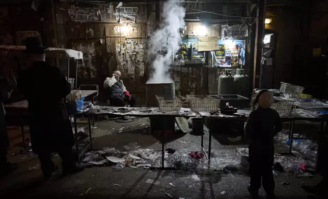 Ultra-Orthodox Jewish men clean their new cooking utensils in a water tank, as preparation for the upcoming Jewish holiday of Passover, in the ultra-Orthodox neighborhood Mea Shearim, in Jerusalem, Thursday, April 10, 2025. (AP Photo/Ohad Zwigenberg)