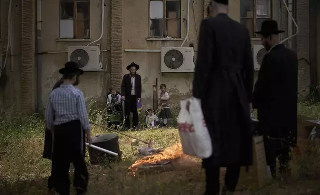 Ultra-Orthodox Jewish men and children look on as leavened items are burnt in final preparation for the Passover holiday in the ultra-Orthodox Jewish town of Bnei Brak, near Tel Aviv, Israel, Friday, April 11, 2025. (AP Photo/Leo Correa)